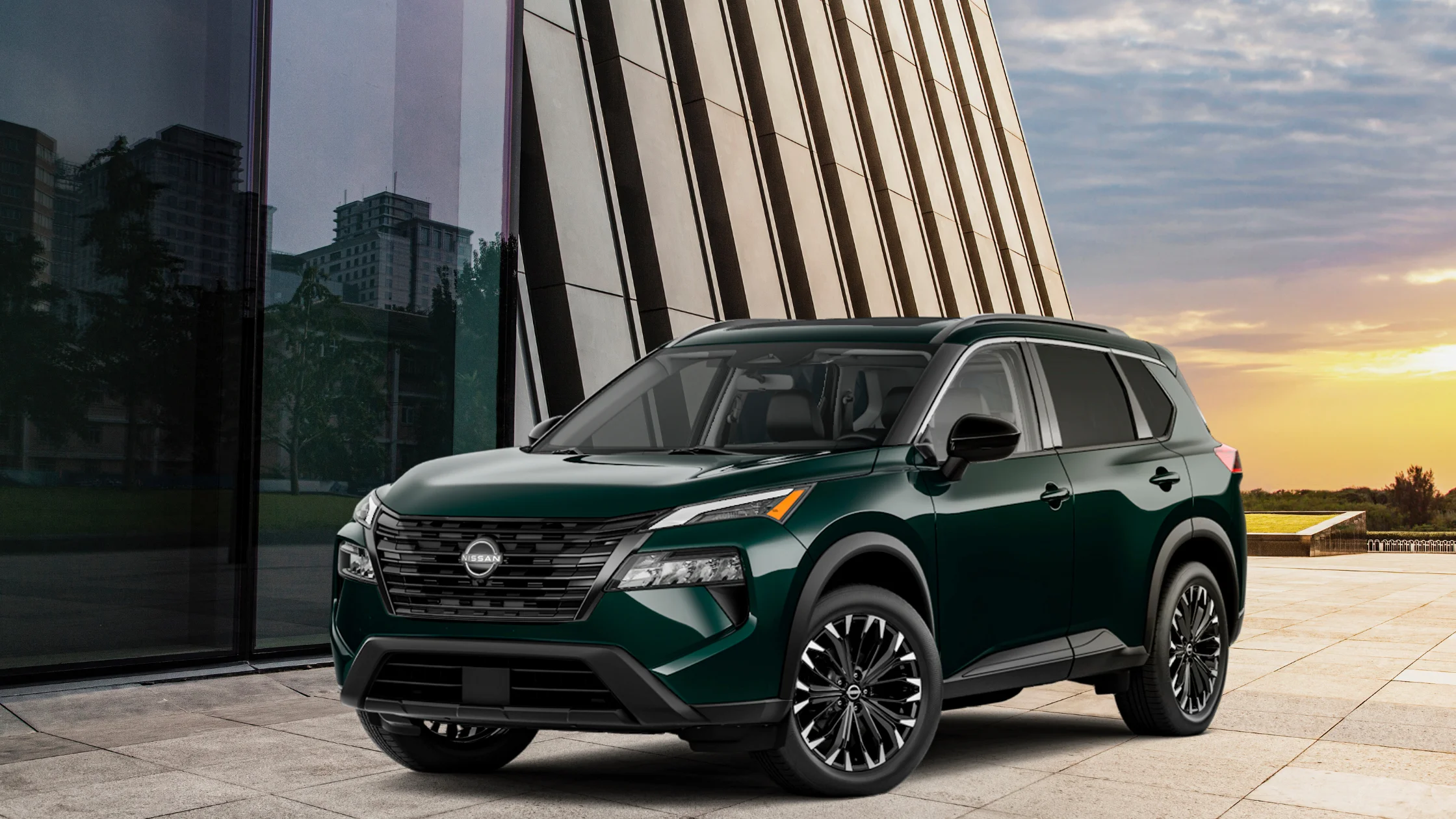 2026 Nissan Rogue® green SUV parked near modern building at sunset with black roof rails