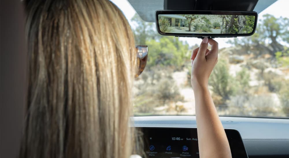 Person using the review mirror in a 2025 Kia Telluride for sale near Golden Valley