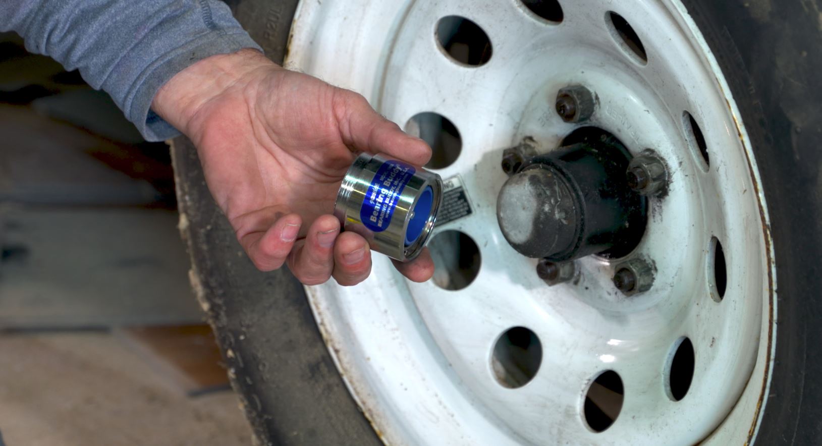 man's hand holding a wheel bearing for a fifth-wheel trailer