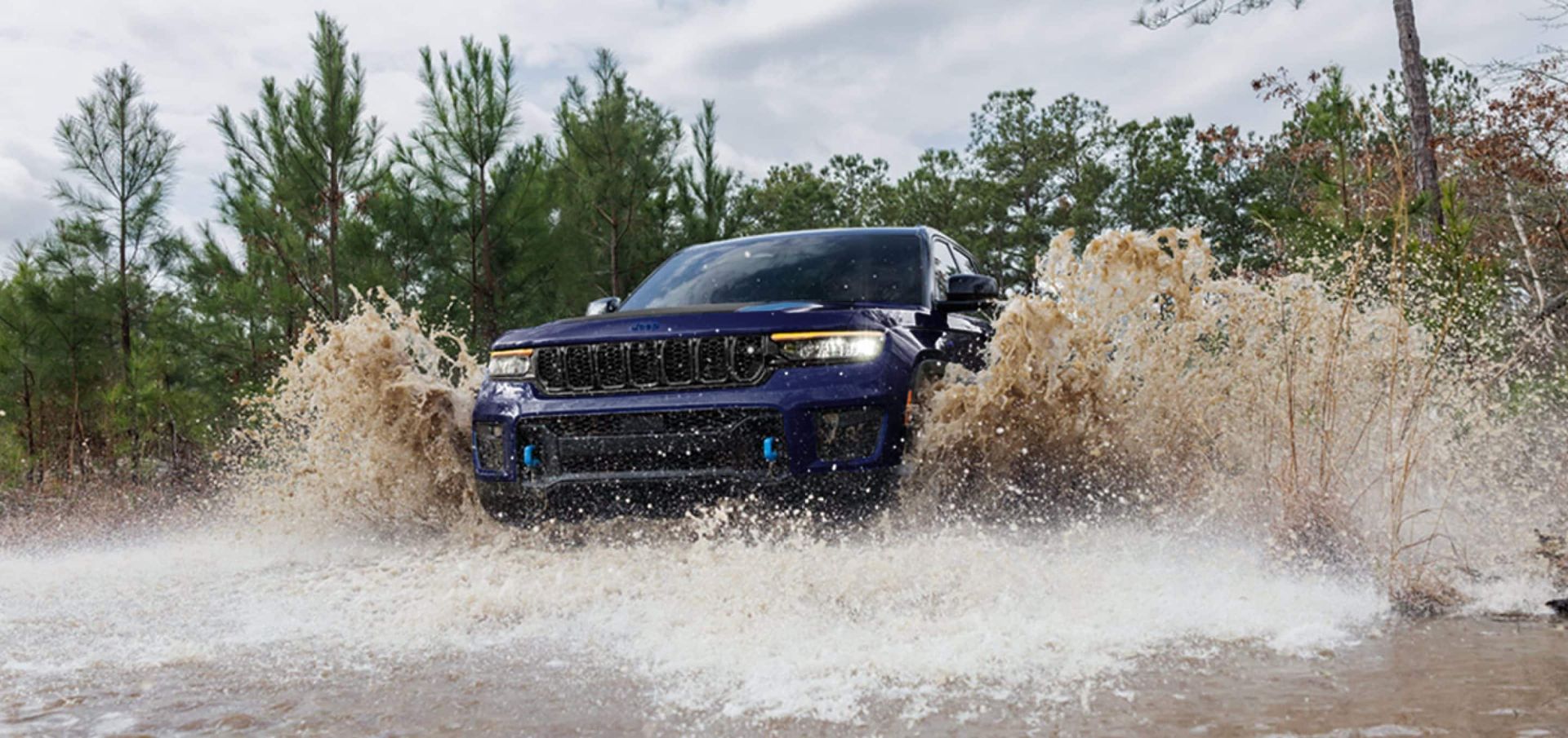 A blue suv driving through water.