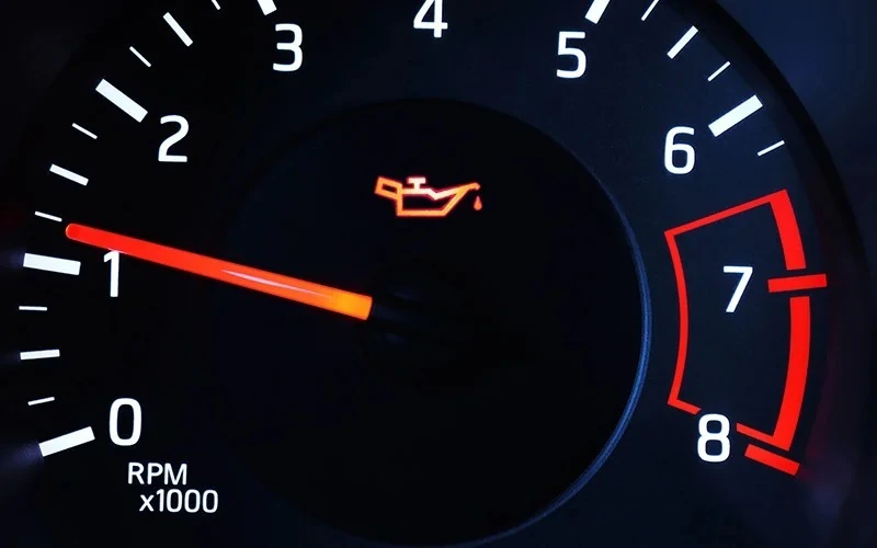 Close-up of a car tachometer with a red oil pressure warning light.