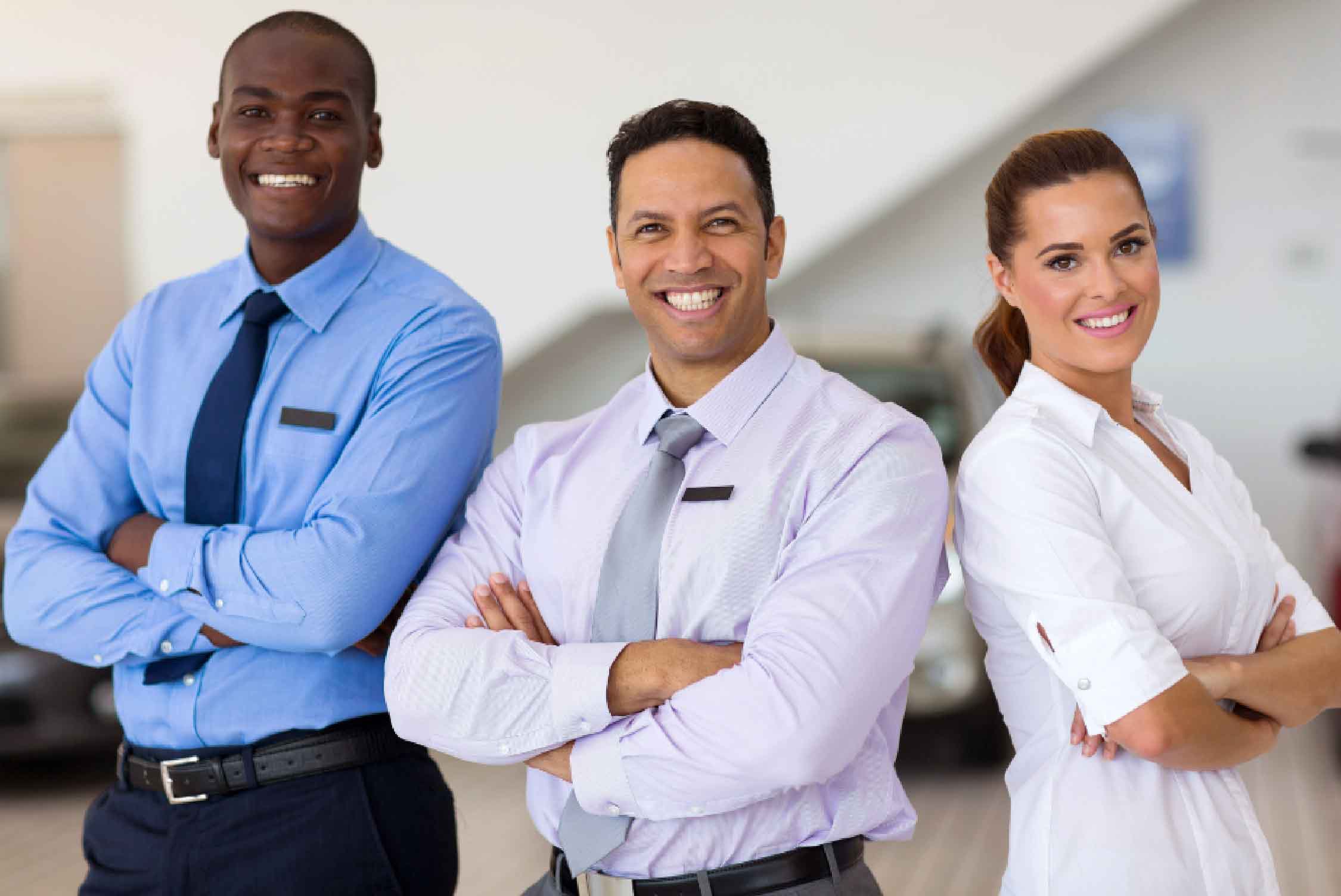 Car salespeople of different genders and nationalities standing with folded arms looking at the camera.