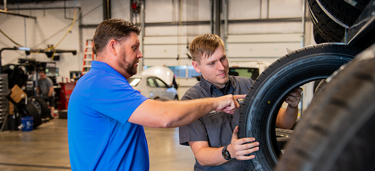 Service manager and technician at Don Hattan Dealerships looking at tire tread while discussing the affect of the tread on the fuel efficiency of the vehicle