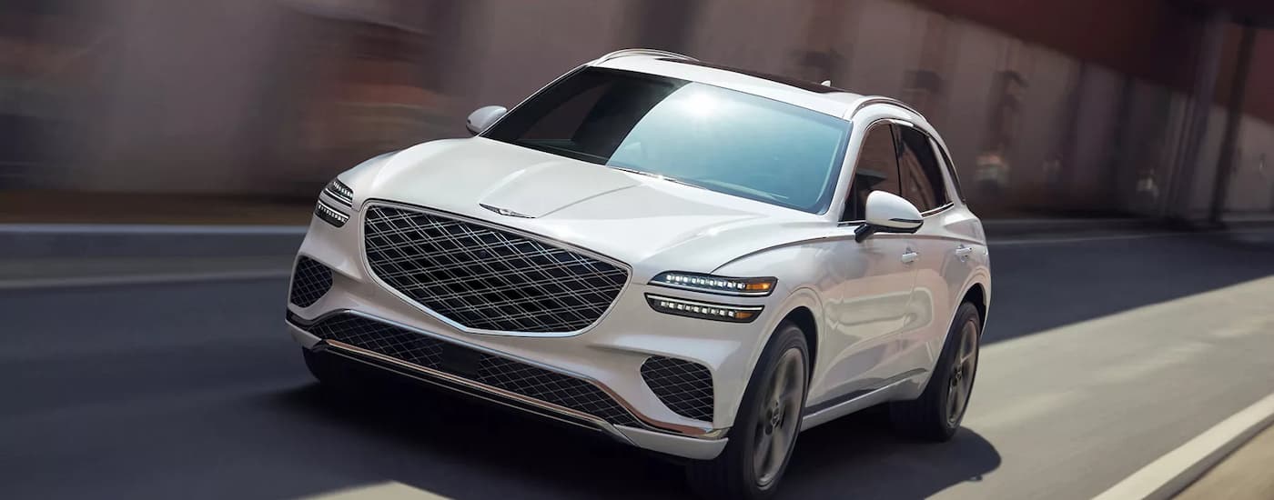 A white 2026 Genesis GV70 driving in a city