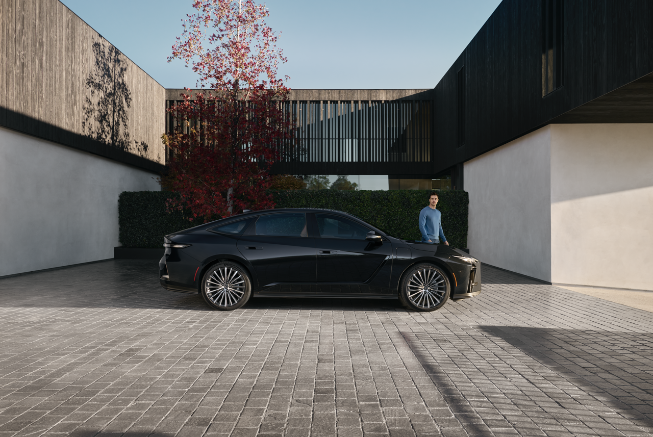ES 350e Luxury EV in Caviar exterior color with optional 21-inch alloy wheels with man standing alongside.