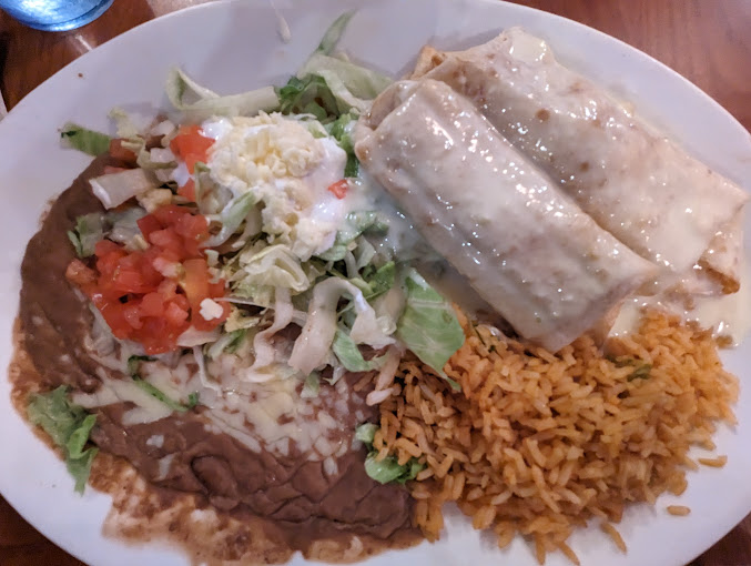 chimichanga dish with rice, beans, and a guacamole salad on the side