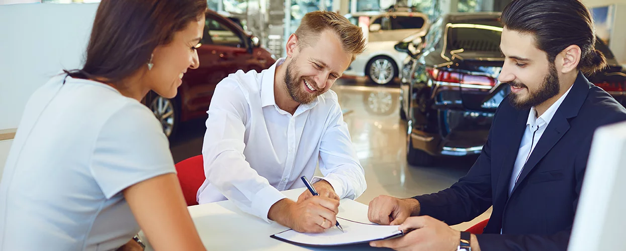 couple speaking with car salesperson at a table in the dealership