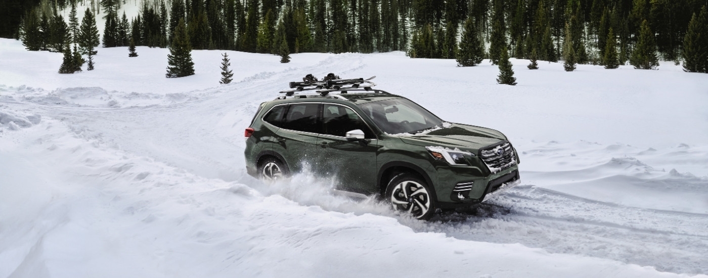 A green 2023 Subaru Forester for sale near Millbrook is shown driving on a snowy trail.