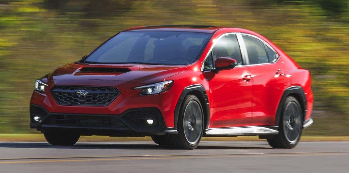 Red Subaru WRX sedan driving on a road