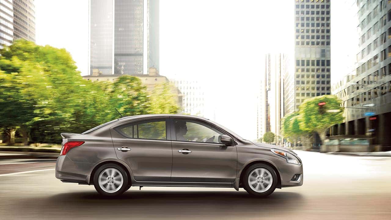 Silver 2017 Nissan Versa sedan on a city street, side profile