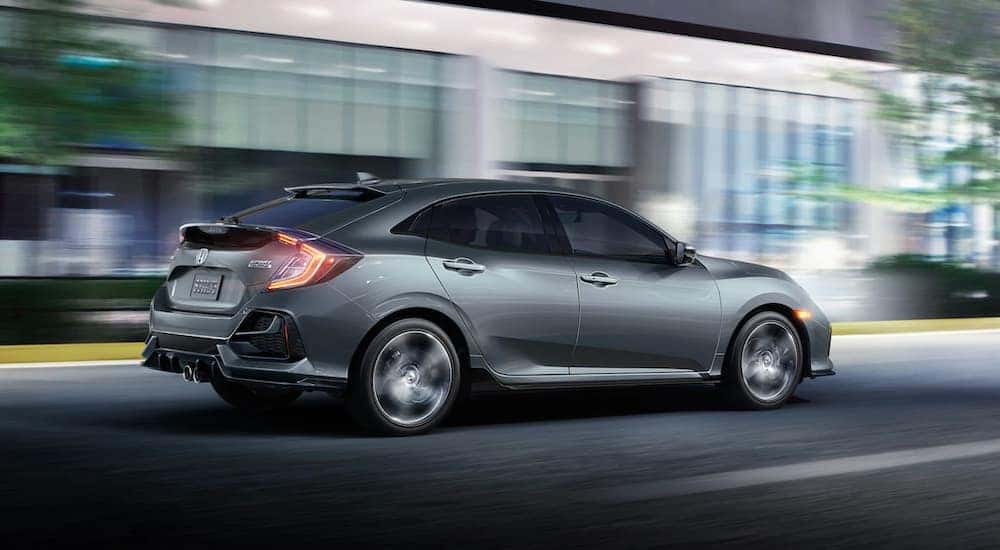 A grey 2021 Honda Civic Hatchback Sport Touring is driving on a city street at night near Rochester, NY.