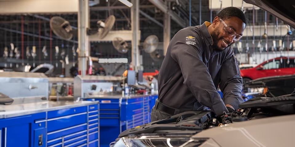 smiling mechanic working on a car engine