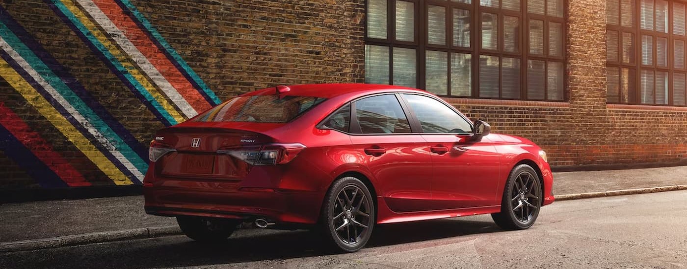 Rear of a red 2024 Honda Civic parked by a brick wall.