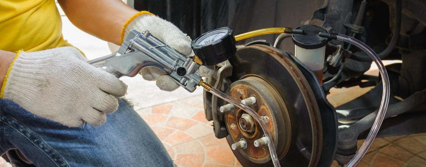 A mechanic is shown flushing the brake lines on a vehicle.