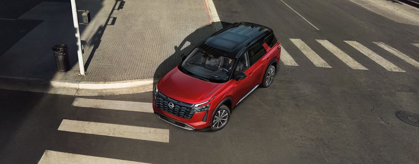 Aerial view of a red 2026 Nissan Pathfinder driving through an intersection.