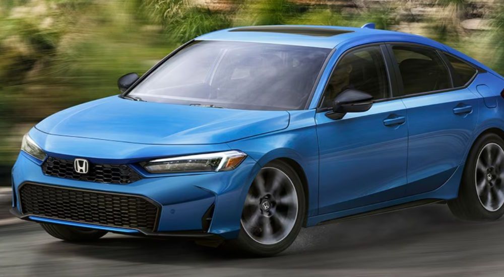A blue 2026 Honda Civic Hatchback turning a corner on the road.