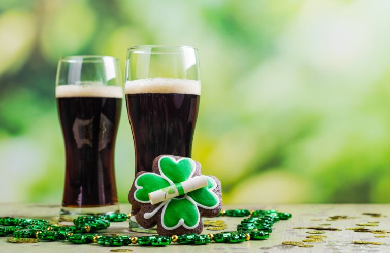 Two Pints of Guinness on a Table with a Shamrock Cookie and Shamrock Necklace