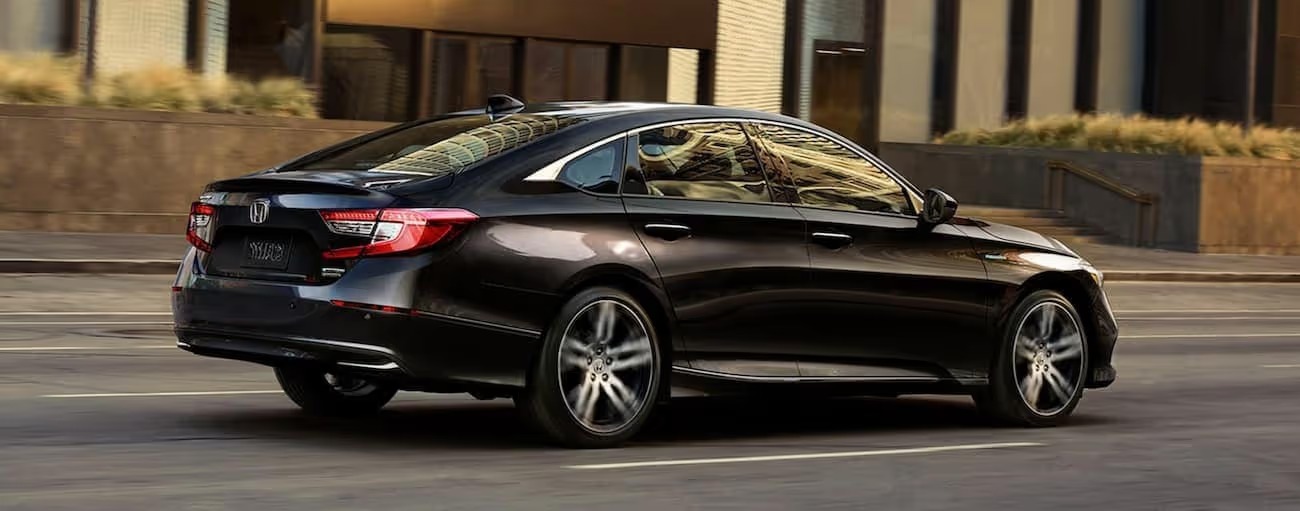 Black 2021 Honda Accord Hybrid is driving on a city street
