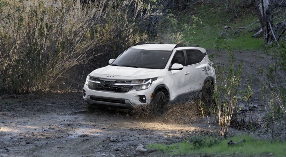 2026 Kia Seltos driving off-road on a muddy path.