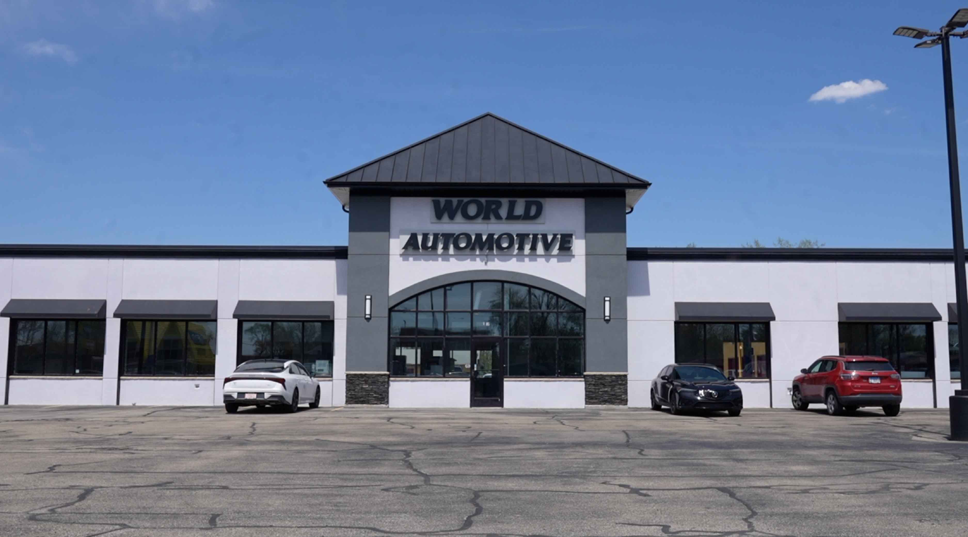 Photo of the front of World Automotive Used Car Lot building located in Joliet Illinois on a sunny day.