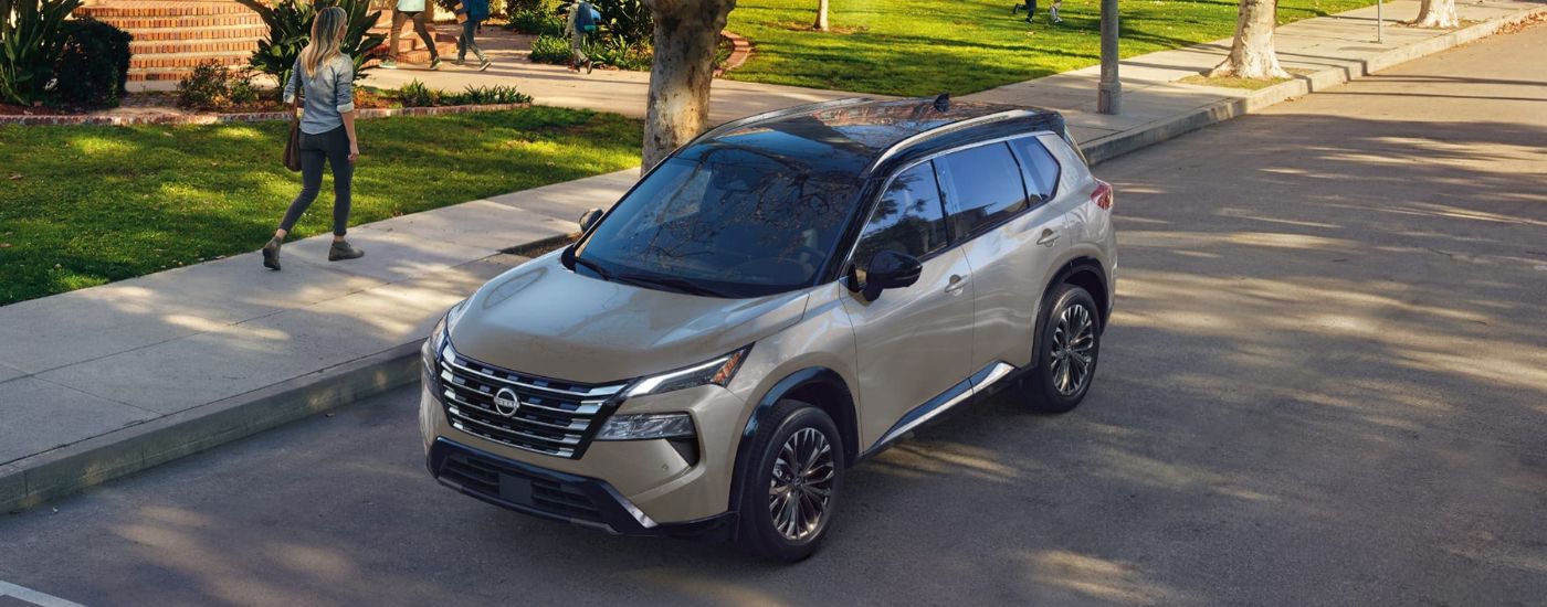 Tan 2026 Nissan Rogue Platinum driving on a street.