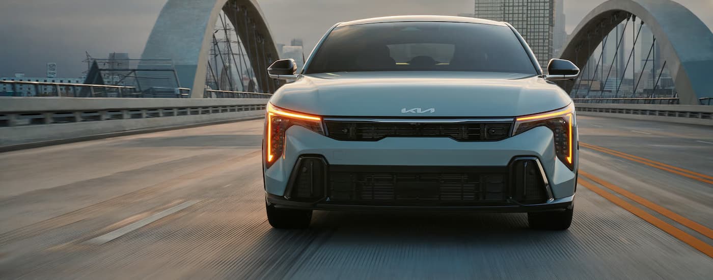 Grey 2024 Kia K4 driving on a city bridge