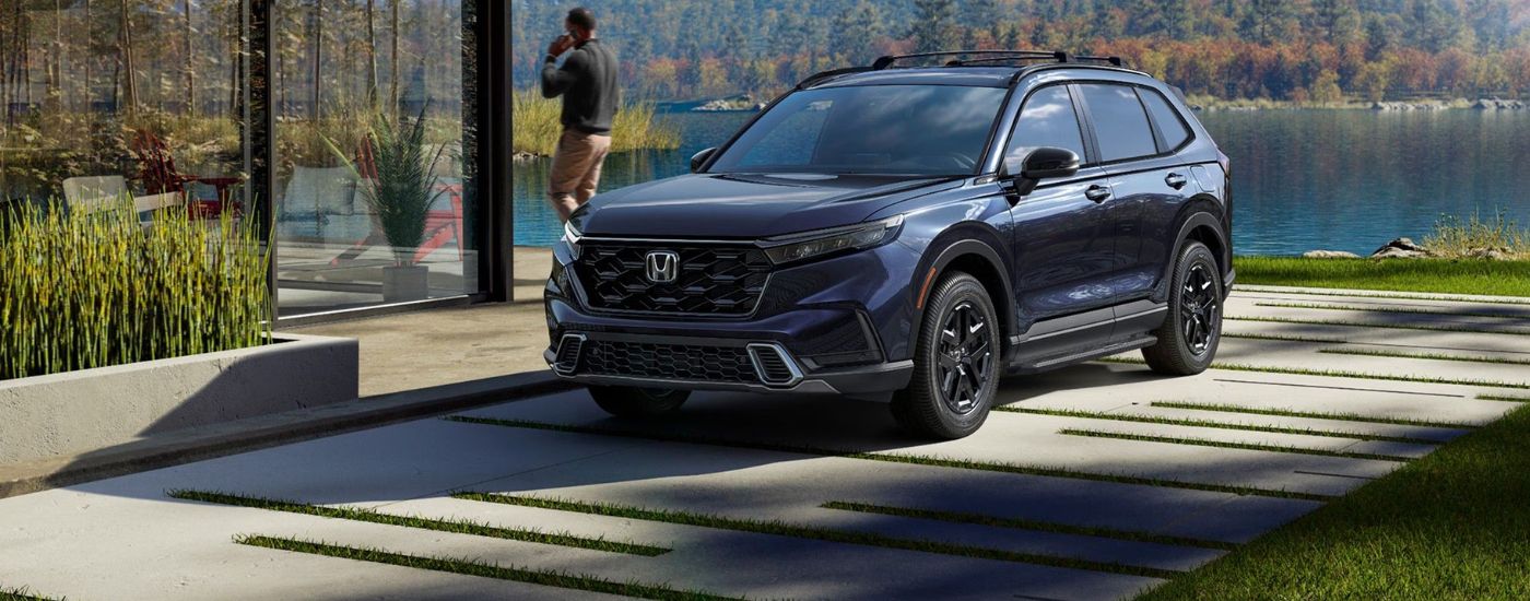 Blue 2026 Honda CR-V parked in a driveway near a lake.