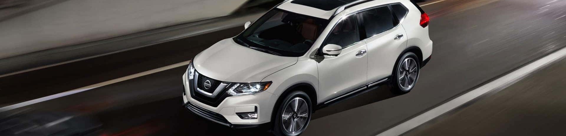 White Nissan Rogue driving through a tunnel with motion-blurred lights