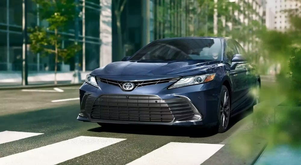 A blue 2023 Toyota Camry driving over a crosswalk.