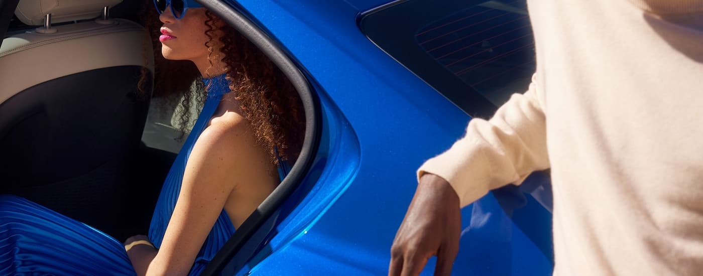 Woman sitting in the back seat of a blue 2026 Genesis G70