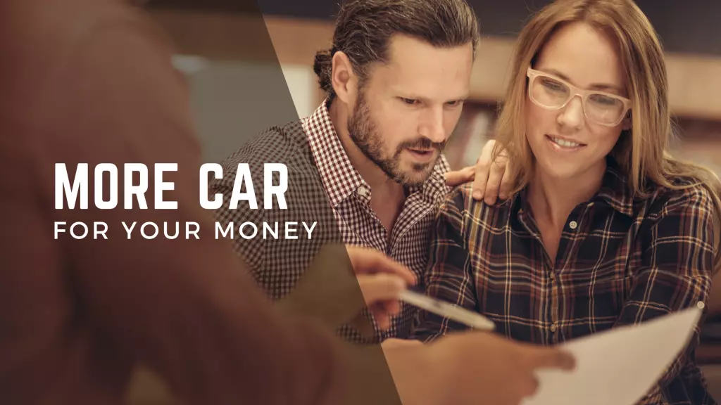 Person not in frame holding a pen and showing a piece of paper to two people, the man looks on confused while the woman looks at the paper like she is understanding, the text More Car For Your Money is taking up the left side of the screen