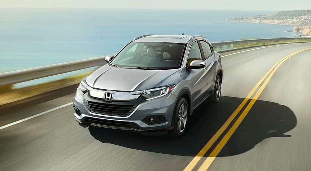 A silver 2020 Honda HR-V EX-L is driving on a coastal highway.