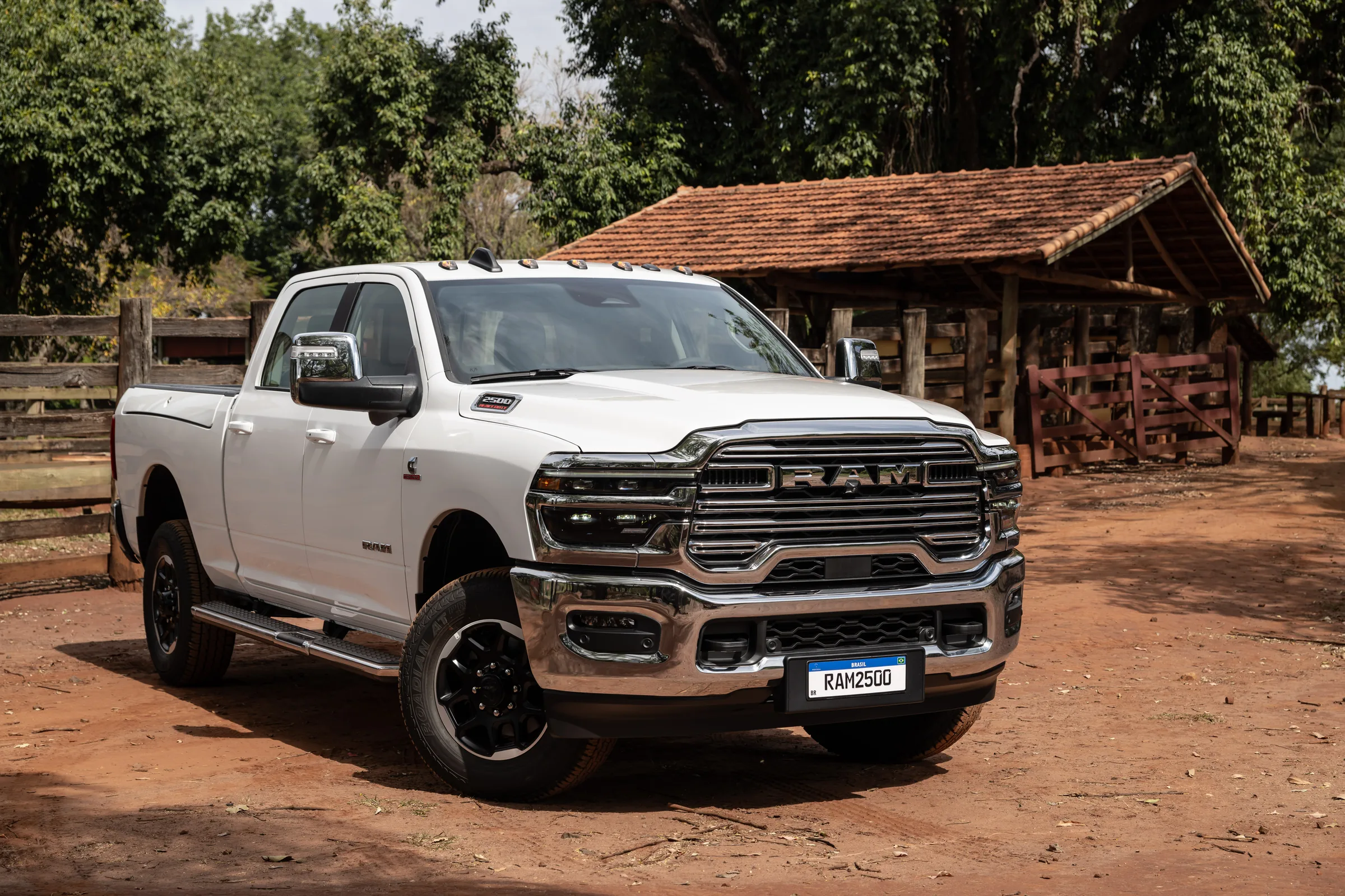 2026 White Ram 2500 Heavy Duty pickup truck parked on a dirt lot in front of a tile-roofed farm outbuilding