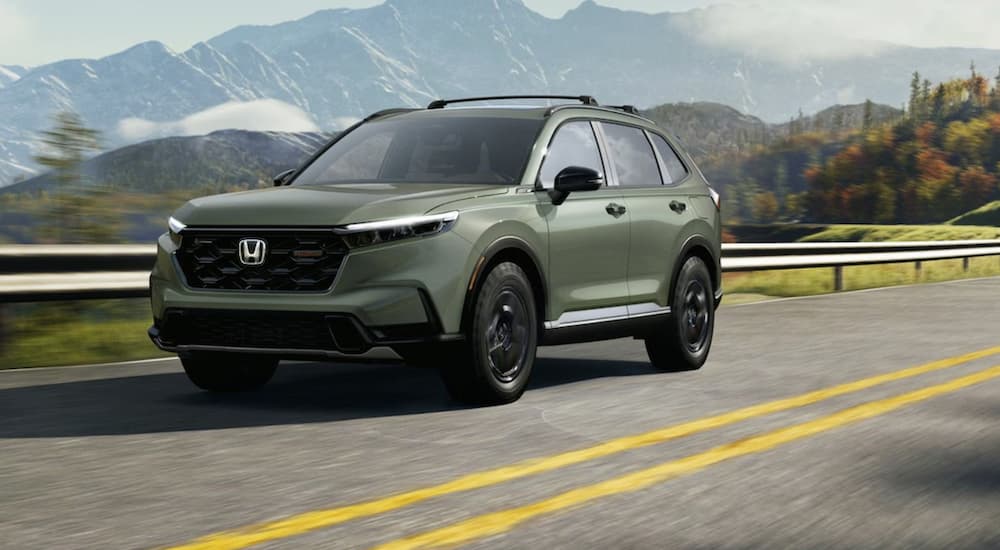 A green 2026 Honda CR-V TrailSport driving down a road