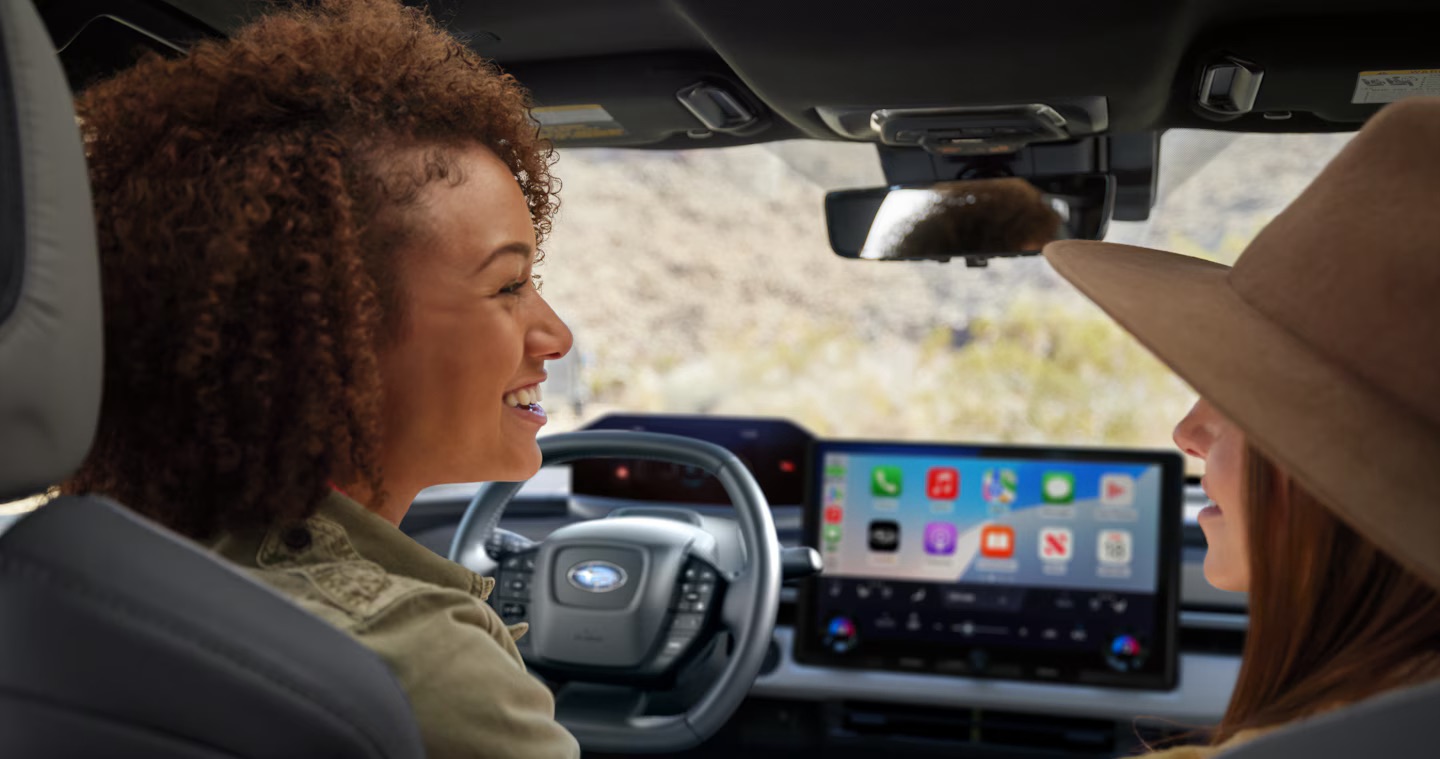 Two women talk in the front seats of a Subaru vehicle