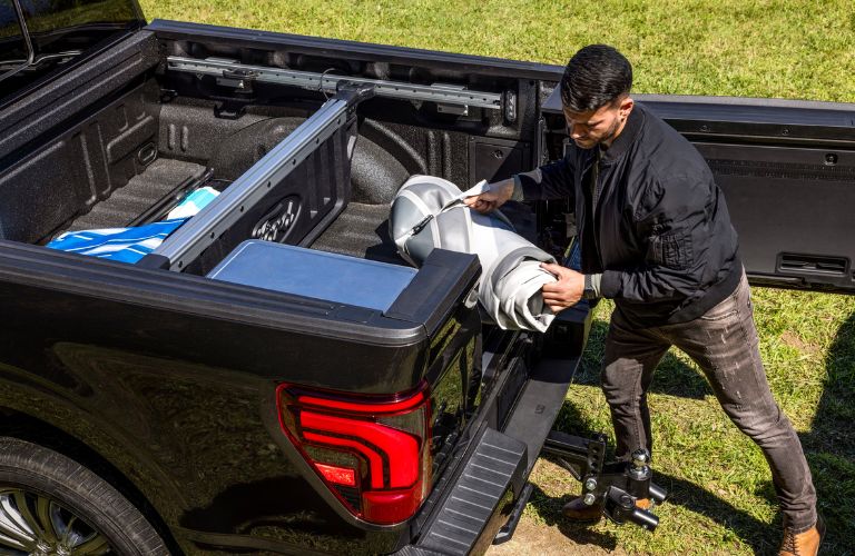 Man Loading Cargo in the 2024 Ford F-150 with a Pro Access Tailgate