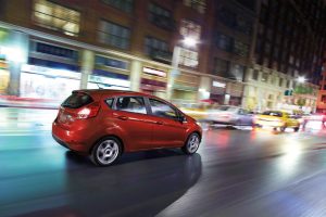 red 2018 Ford Fiesta Hatchback driving down a city street