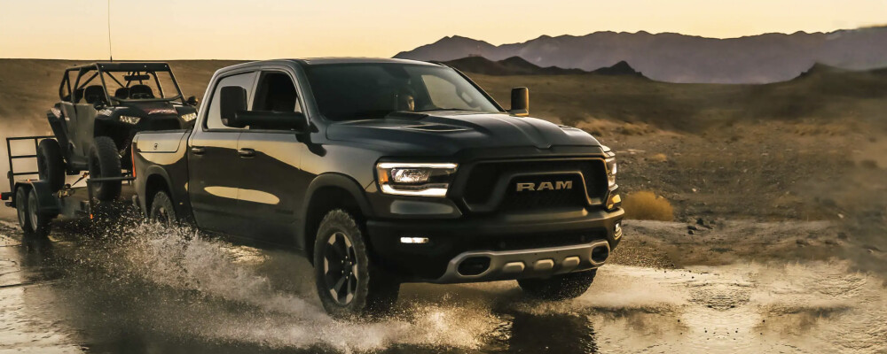 2022 RAM 1500 towing an ATV through large puddle