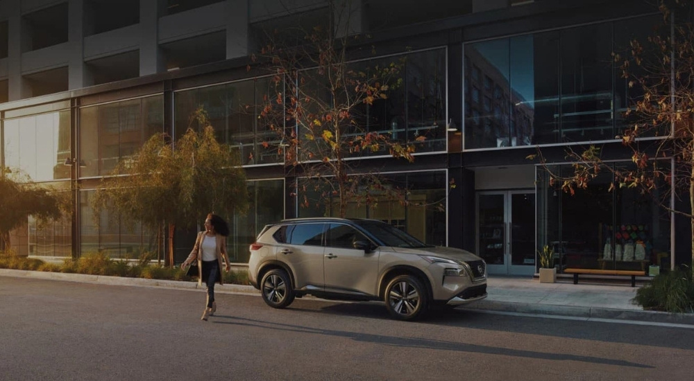 Woman walking past a grey 2023 Nissan Rogue