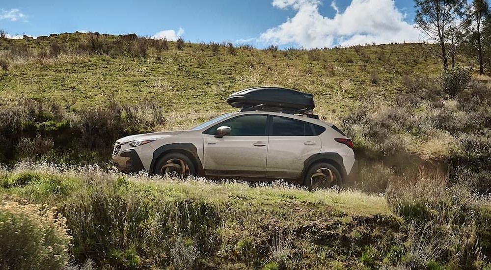 A tan 2026 Subaru Crosstrek Hybrid driving uphill.