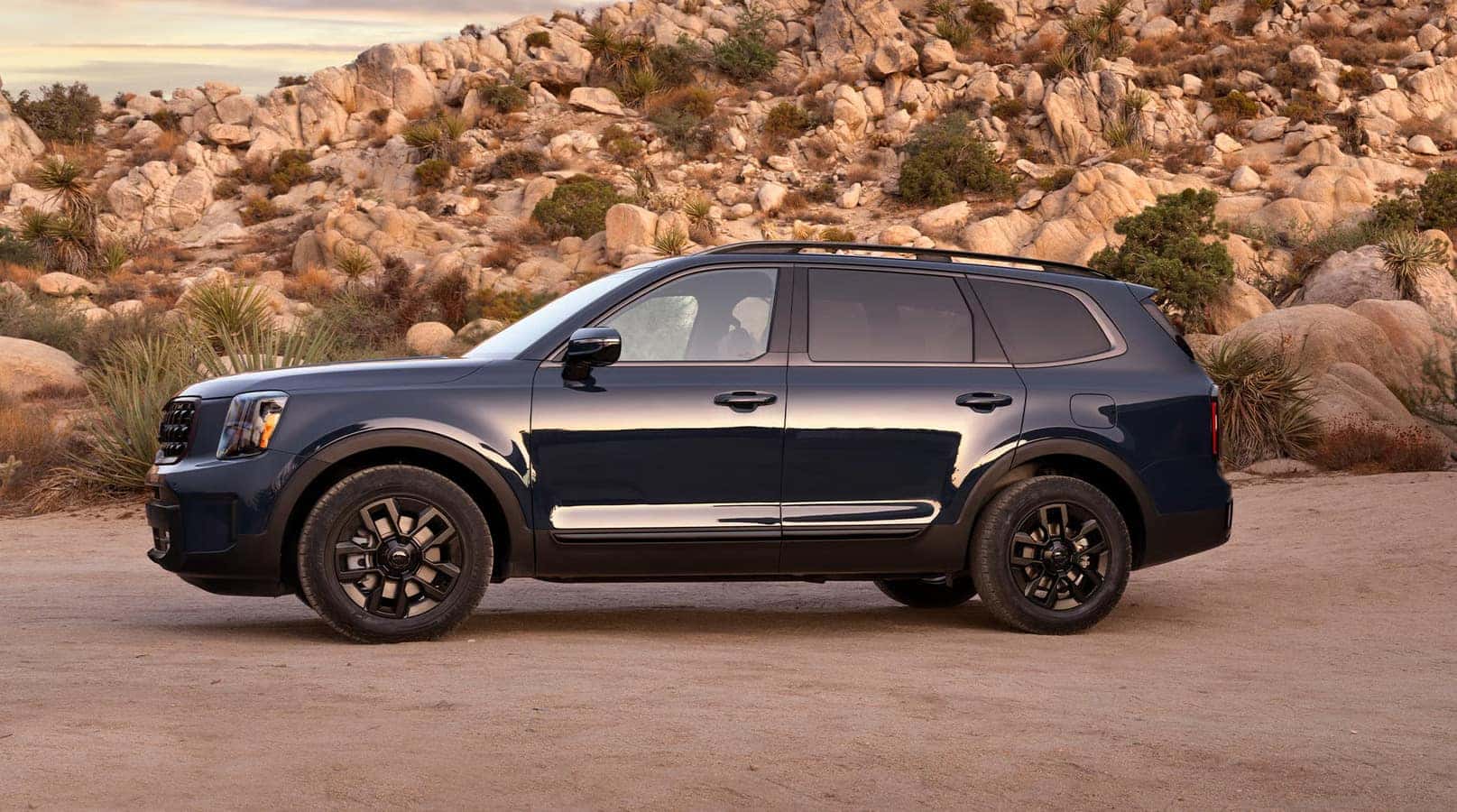 Kia Telluride SUV parked in a rugged outdoor setting, showcasing its sleek design and off-road capability, ideal for summer road trips and family adventures.