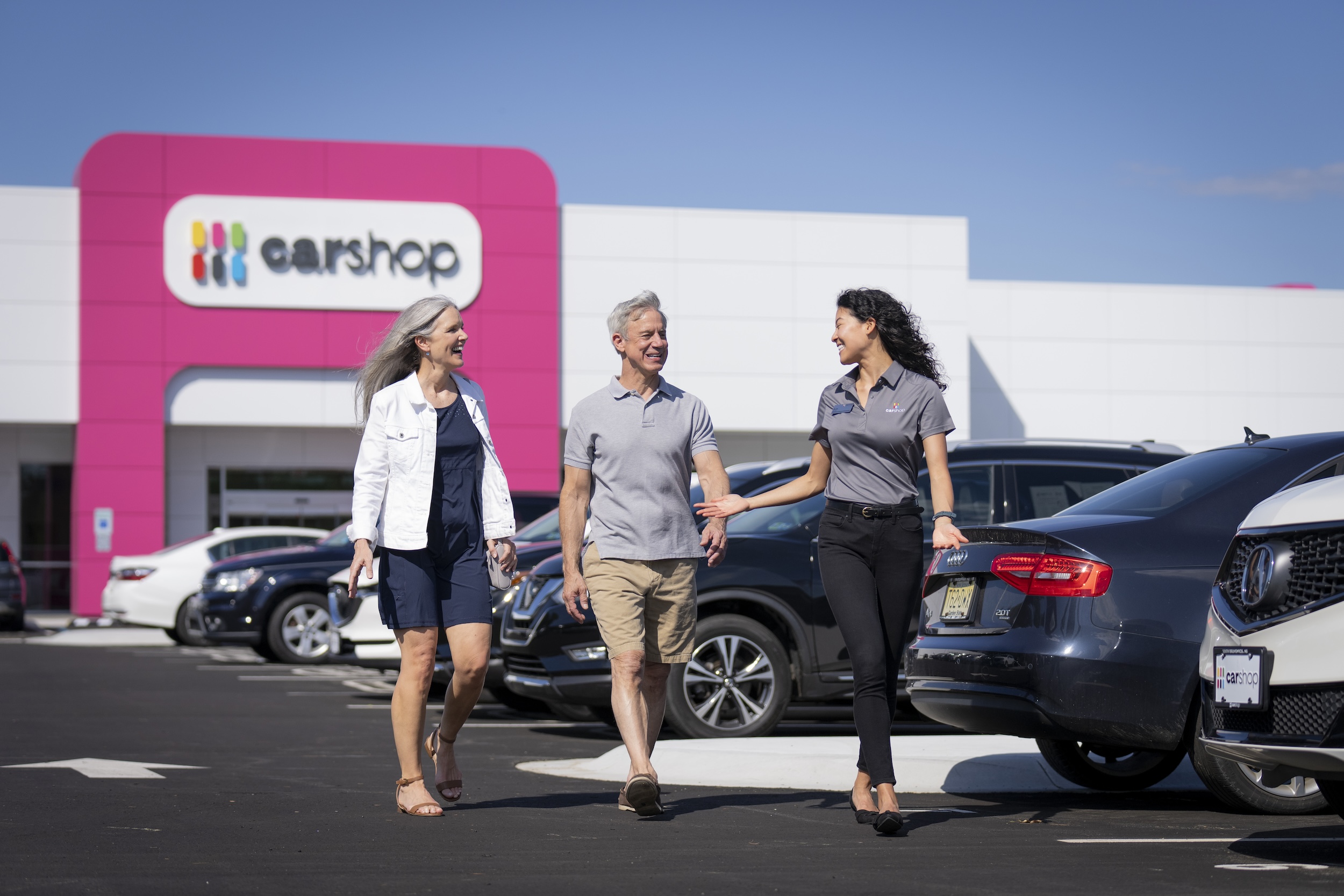 Associate walking with two clients through Carshop lot