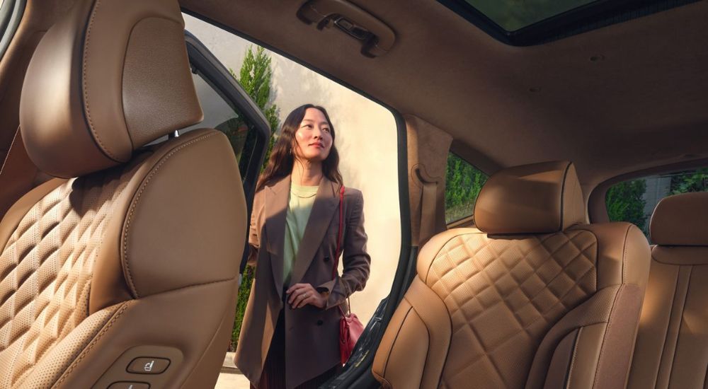 A woman looking at the tan interior of a 2027 Genesis GV80.