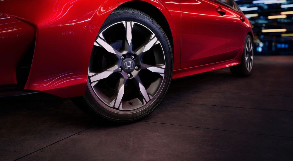 Close up of tires on a red 2026 Honda Civic Sport Touring Hybrid at night.
