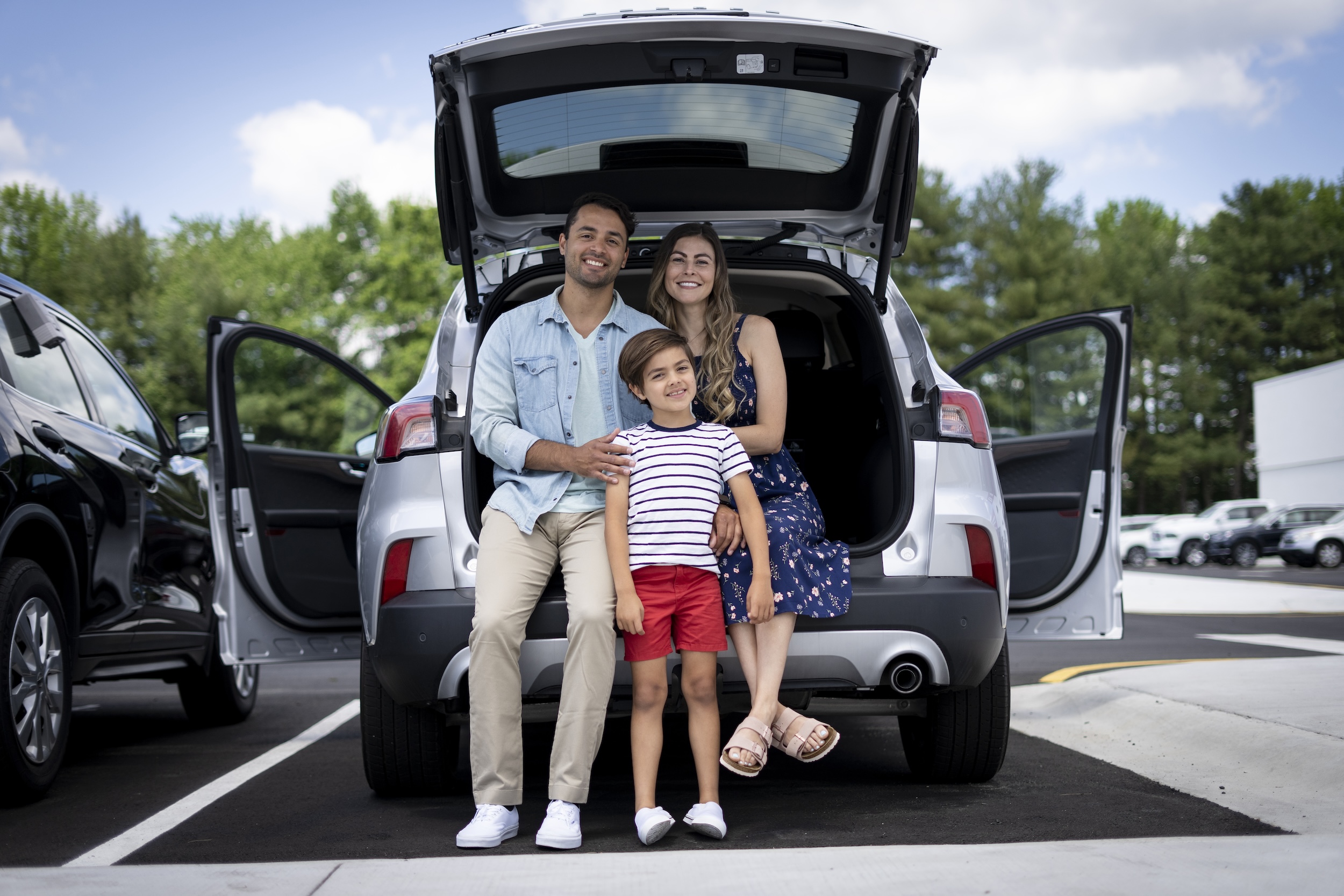 Family smiling and sitting in back of SUV. 