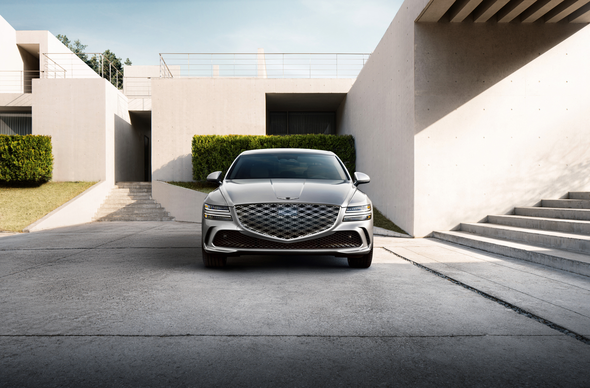 Front view of grille details on Genesis G80 in Ceres Blue parked in front of modern house