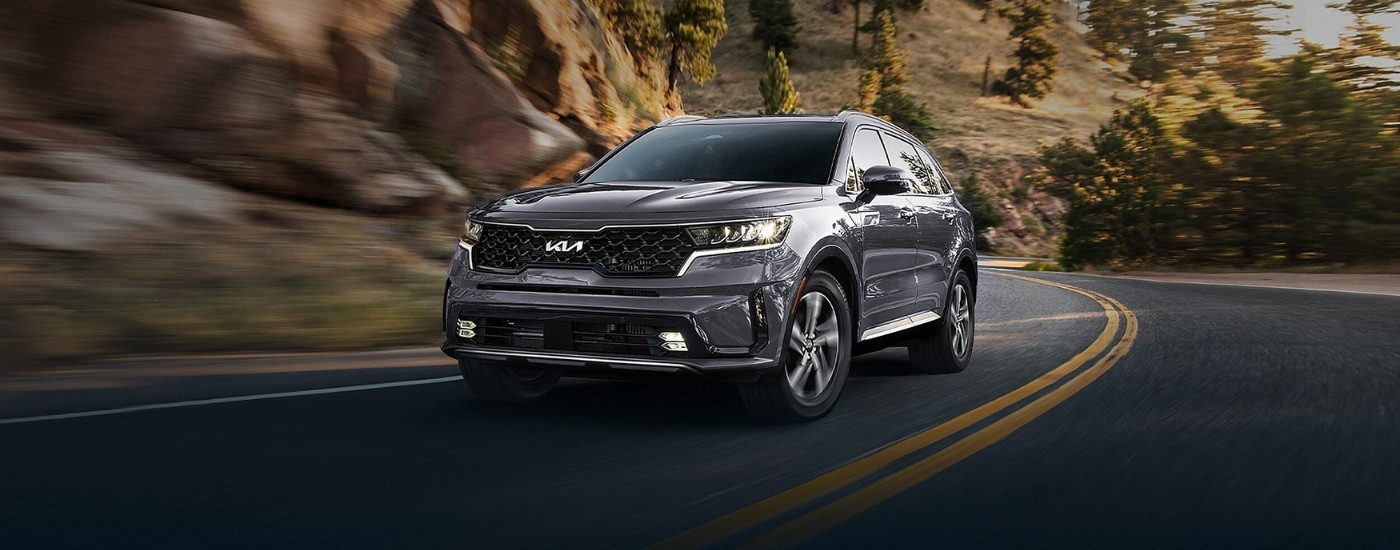 Grey 2023 Kia Sorento Hybrid driving around a corner