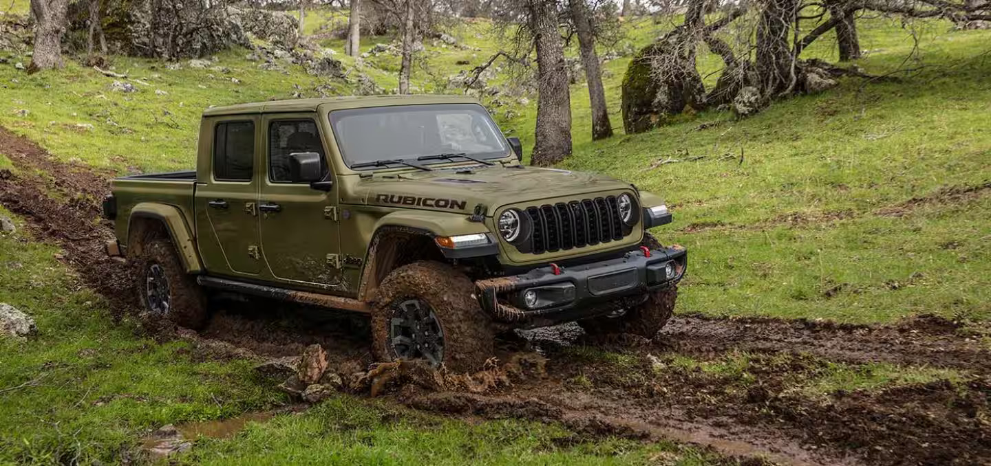 A green jeep griving through the mud.