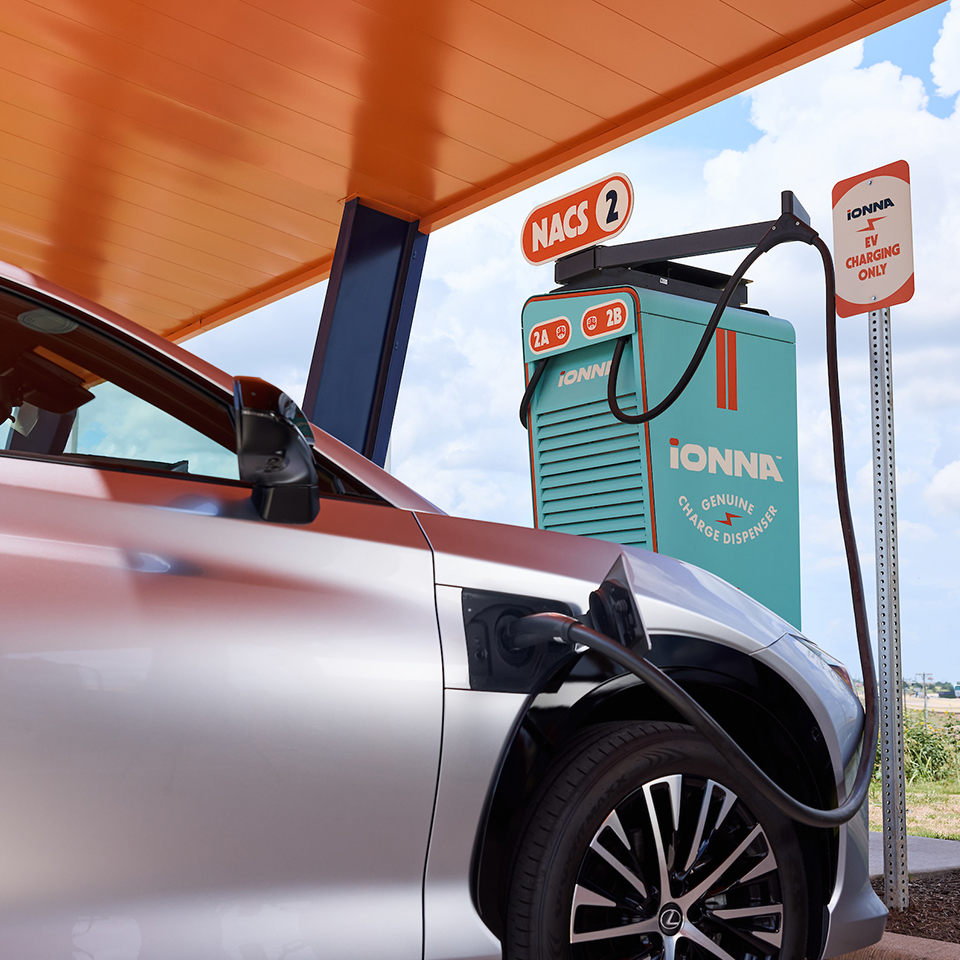 An electric car plugged into an IONNA charging station. 