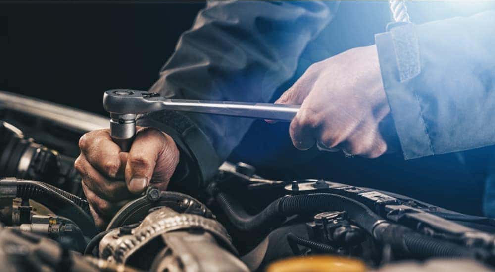A mechanic using a socket wrench on a car engine